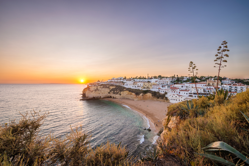 Sunset over whitewashed coastal town and crescent-shaped beach